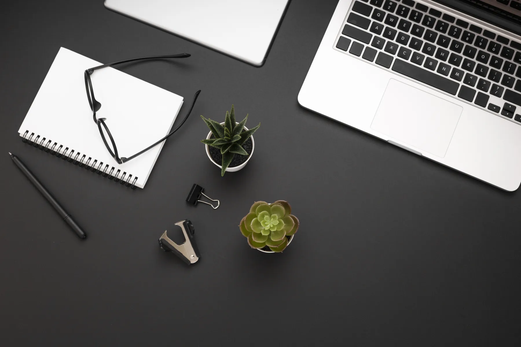A focused technical workspace with a laptop, notebook and planning tools