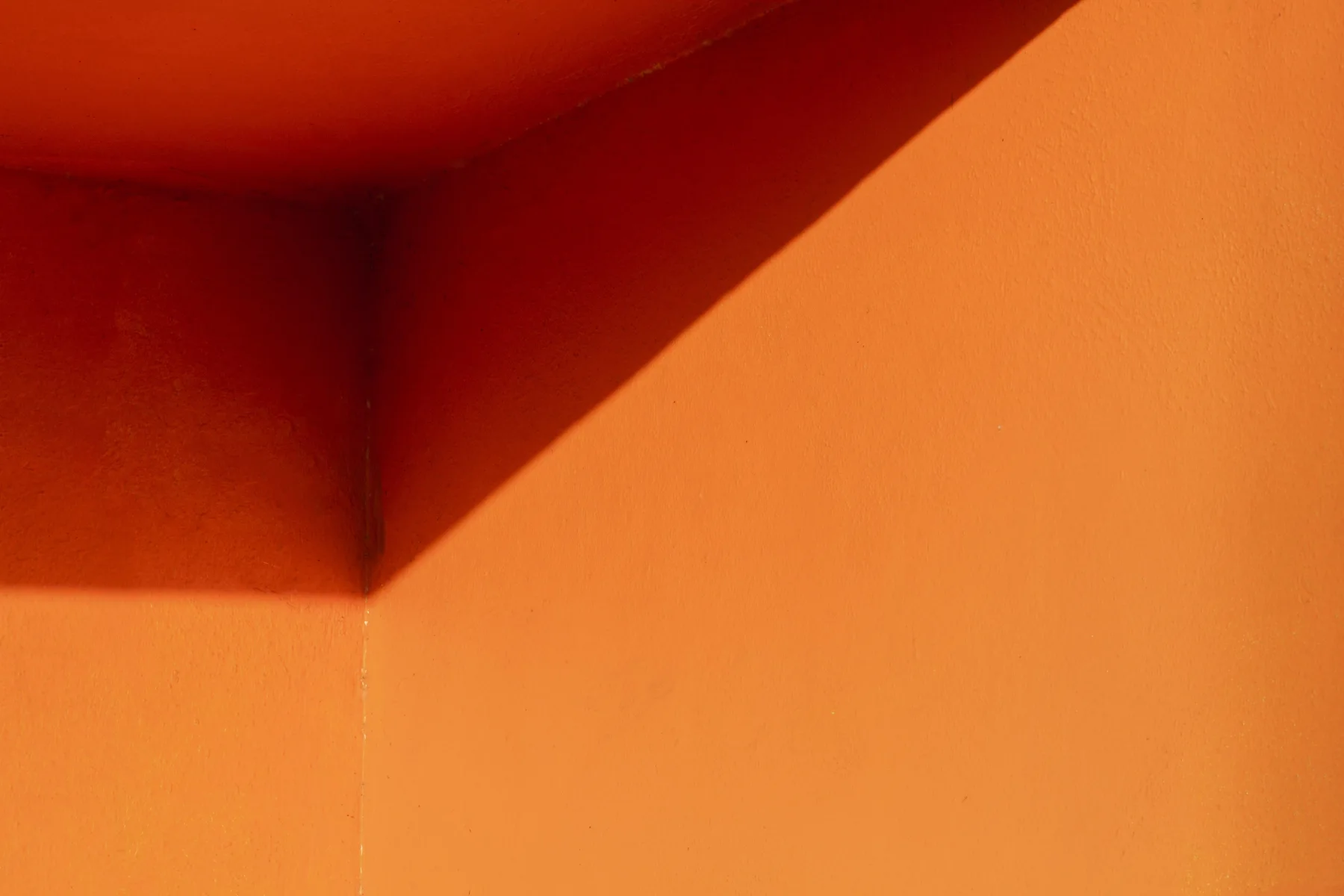 Sunlight and a diagonal shadow on an orange wall
